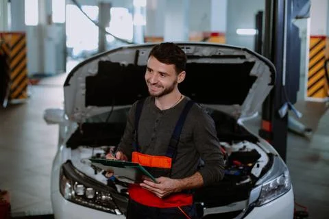 Mechanic man in a uniform write the problem of the car in a map in the modern Foto stock