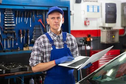 Mechanic man using laptop checking car in workshop 写真素材