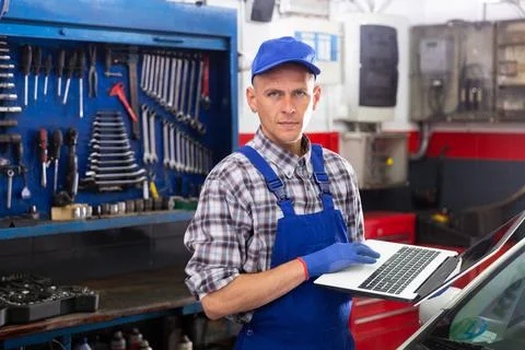 Mechanic man using laptop checking car in workshop Stock Photos