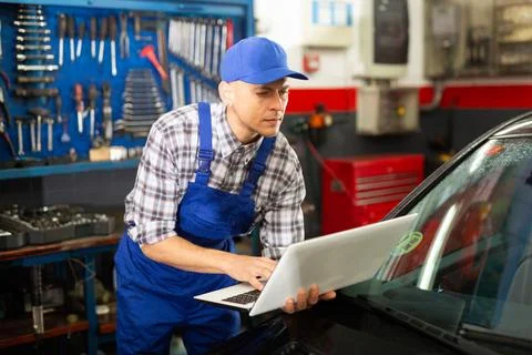 Mechanic man using laptop checking car in workshop 写真素材
