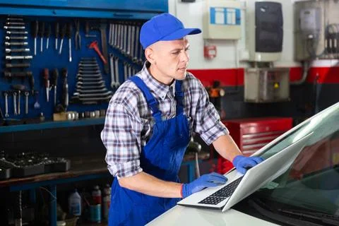 Mechanic man using laptop checking car in workshop 写真素材