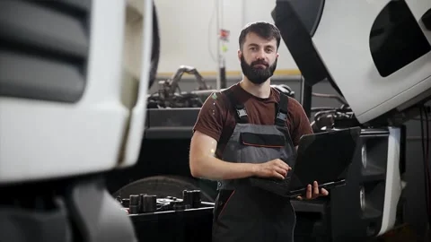Mechanic man using laptop for truck diagnostics in maintenance garage, vehicle Stock Footage 333705836