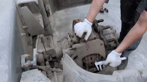 Mechanic man in work gloves measuring the thickness of the brake pads on a lorry Stock Footage 154411023