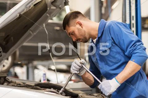 Mechanic man with wrench repairing car at workshop Stock Photos
