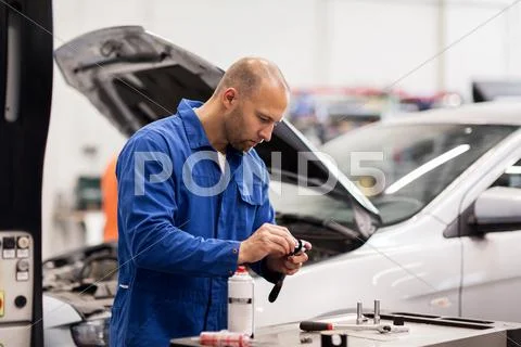 Mechanic man with wrench repairing car at workshop Stock Photos
