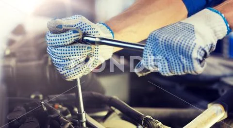Mechanic man with wrench repairing car at workshop Stock Photos