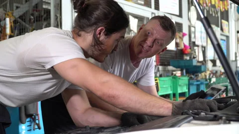 Mechanic manager man checking car with assistant worker using tablet in works Stock Footage 147369147