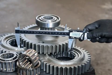 Mechanic measuring the outer diameter of an industrial gear using a digital.. Stock Photos