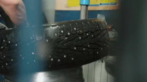 Mechanic mounting studded winter tire on rim Stock Footage 337829627