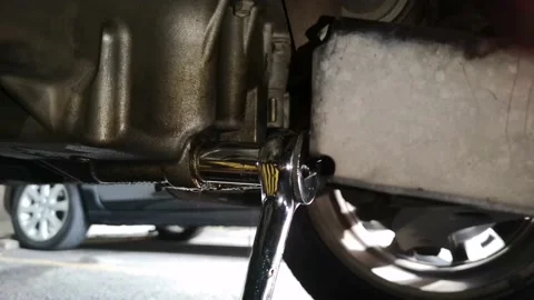 Mechanic is opening the screw plug on the car engine oil drain Stock Footage 131540296
