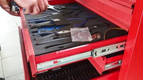 The mechanic opens a red metal box and puts there tools Видео 123584189