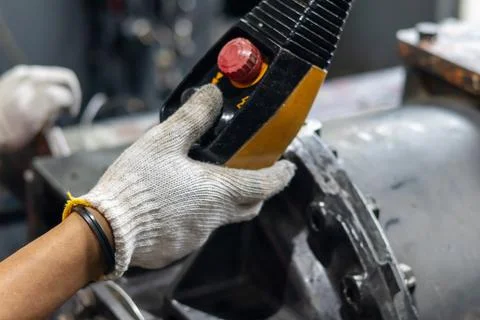 Mechanic operates crane pendant control to lift heavy industrial machinery .. Stock Photos