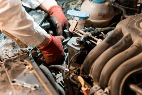 Mechanic Performing Engine Repairs in a Well-Worn Car Engine Bay Fotos de archivo