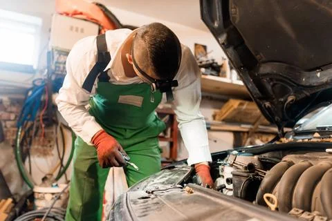 Mechanic Performing Maintenance on Car Engine in Workshop Stock Photos
