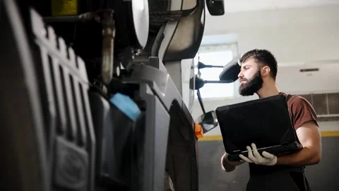 Mechanic performing truck diagnostic using laptop for vehicle repair Stock Footage 333705828