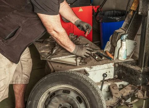 Mechanic picks up a tool to remove the valve of a car Stock Photos