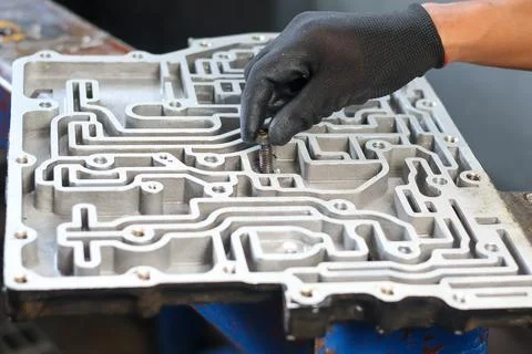 Mechanic placing a bolt into an automatic transmission valve body. Stock Photos