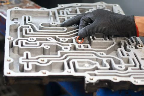 Mechanic placing an O-ring on an automatic transmission valve body. Stock Photos