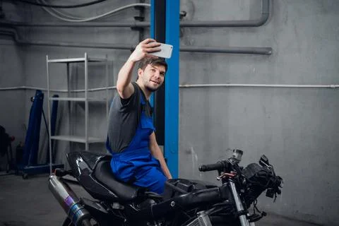 Mechanic posing for a photo while sitting on a bike Stock Photos
