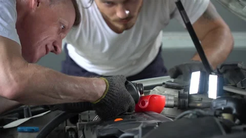 Mechanic pouring oil to car engine in workshop at auto car repair service cen Stock Footage 147369587