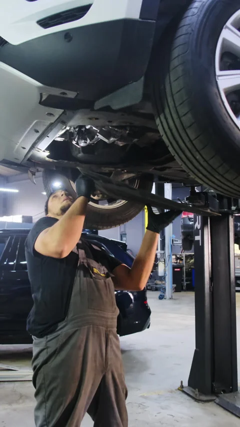 Mechanic prepares to install protective panel on bottom of car Stock Footage 317653035
