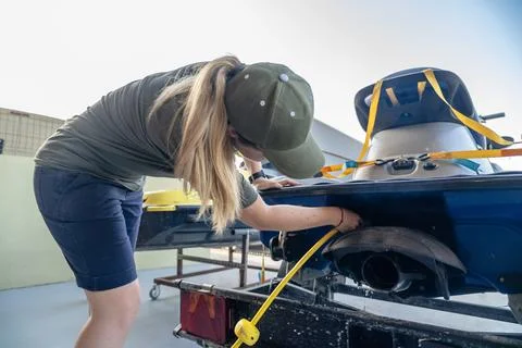 Mechanic preparing jet ski for launch, connecting drainage tube Stock Photos