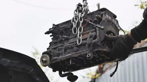 Mechanic pulling car engine block with chain hoist during vehicle maintenance Fotos de archivo
