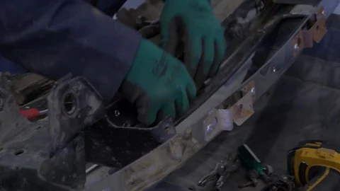 A mechanic pulling a rivet out of a car bumper Stock Footage 77109596