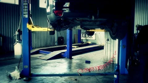 Mechanic push red tools box under lifted car Stock Footage 74206588