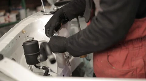 Mechanic in red overalls assembles the car, hands close-up Stock Footage 58135036