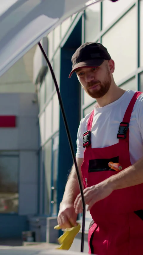 Mechanic in red overalls working on car engine with diagnostic computer Stock Footage 320394356
