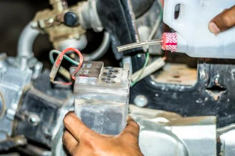 A mechanic is refiling the battery of a motorcycle Foto stock
