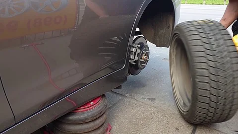 Mechanic removes the wheel from the vehicle, standing on the Jack Video stock 120939953