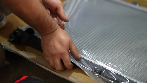 Mechanic Removing Plastic Wrap from Radiator Core Stock Footage 345567926