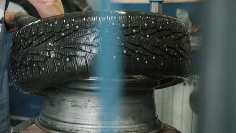 Mechanic removing studded winter tire from rim in garage Stock Footage 337829575