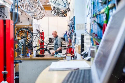 Mechanic Repairing Bicycle In Workshop