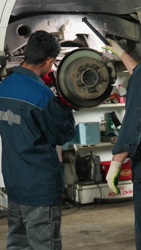 Mechanic Repairing Car While Lab Technicians Observe and Take Notes in Workshop Stock Footage 318201472