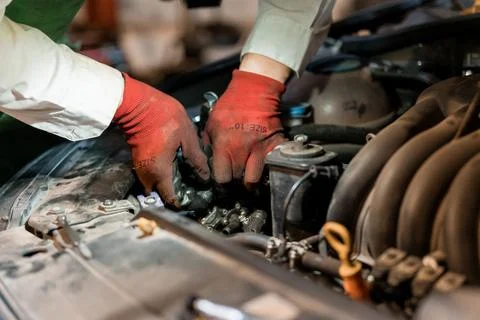 Mechanic Repairing Engine Components with Red Work Gloves 库存照片