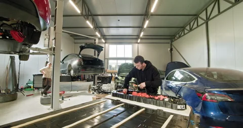 Mechanic Repairing EV Battery Module in Modern Workshop Stock Footage 277302299