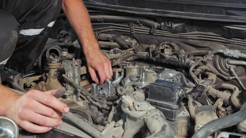 The mechanic repairs the car engine under the hood. Close-up in 4K (UHD) Stock Footage 120141899