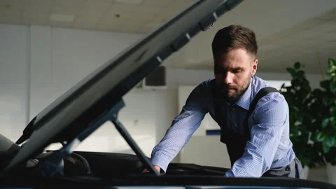 Mechanic repairs a car engine under the open hood in garage Stock Footage 300613073