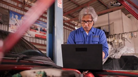 Mechanic repairs the damage using the pc under the hood in car service. Video stock 93379276