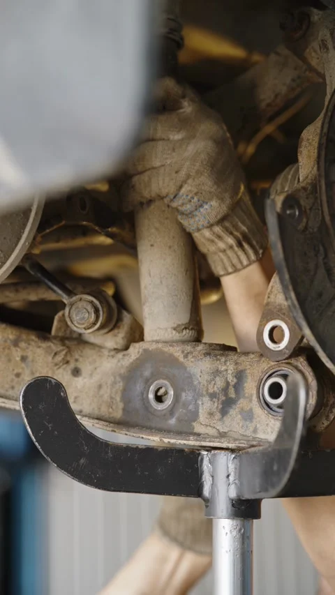 Mechanic repairs rusty car rear suspension with coil spring undercarriage Stock Footage 337569454