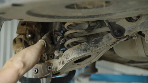 Mechanic repairs rusty car rear suspension with coil spring undercarriage Stock Footage 337569728
