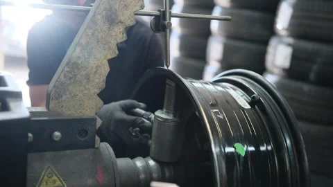 A mechanic repairs a wheel rim using a special device for repairing car rims Stock Footage 306883100