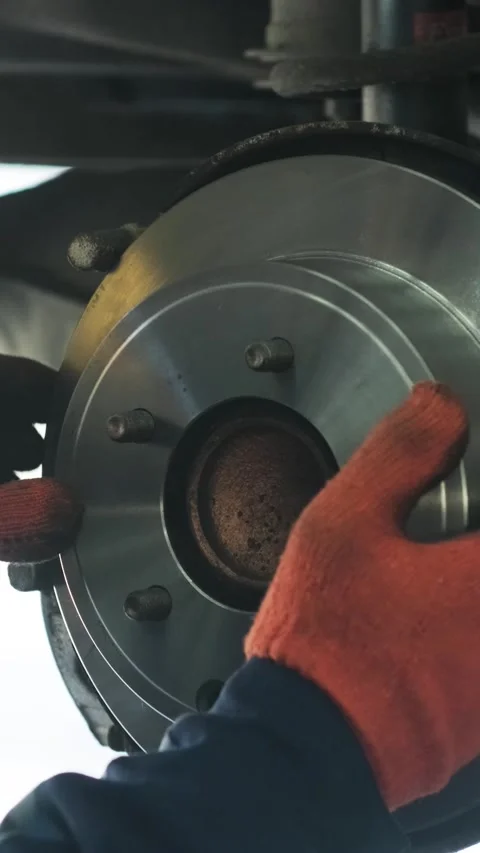 Mechanic replacing brake disc and pads on car in garage Stock Footage 332858429