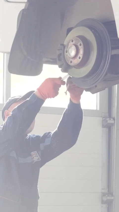 Mechanic replacing brake disc and pads on car in garage Stock Footage 332858514