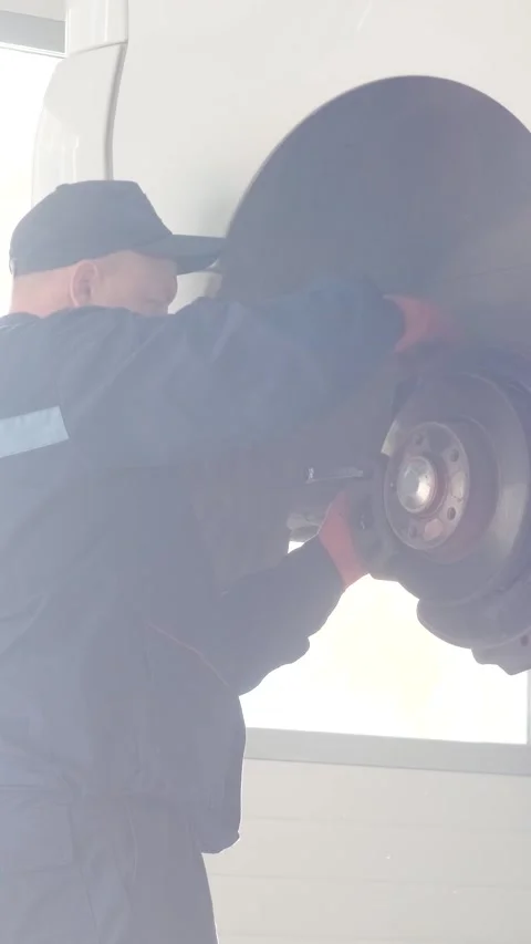 Mechanic replacing brake disc and pads on car in garage Stock Footage 332858515