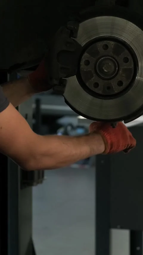 Mechanic replacing brake disc and pads on car in garage Stock Footage 332858549