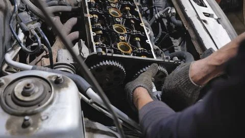 Mechanic replacing car engine timing belt during automotive repair and Stockfoto's